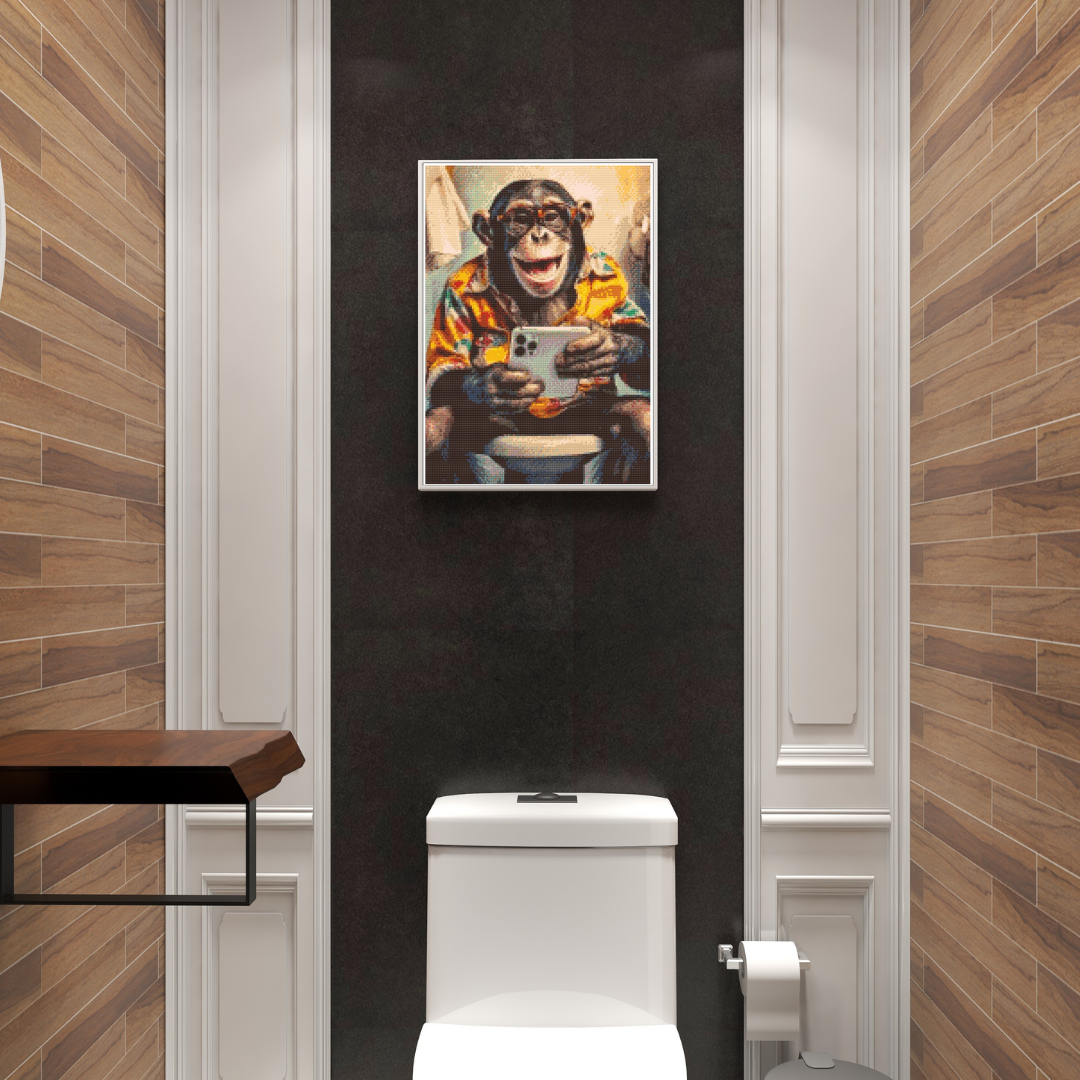 Diamond painting af en abe med briller på toilettet, iført farverig skjorte og med en mobiltelefon i hånden.